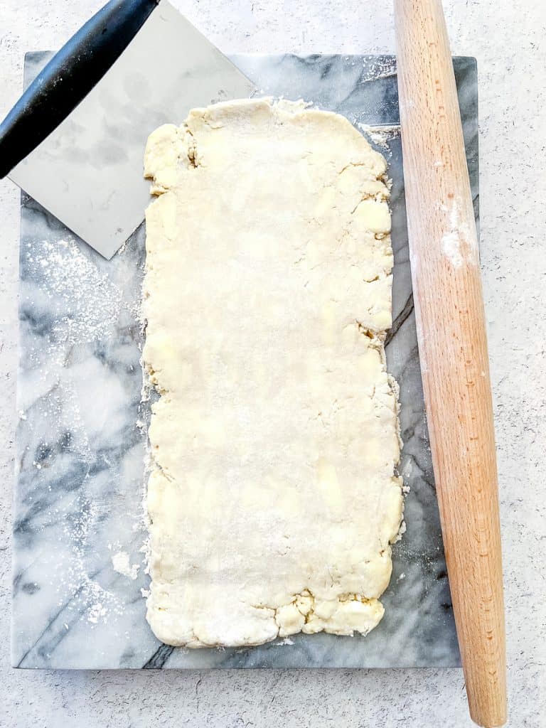 Rolling a piece of puff pastry dough out to a twelve inch by six inch rectangle, to start the first fold.