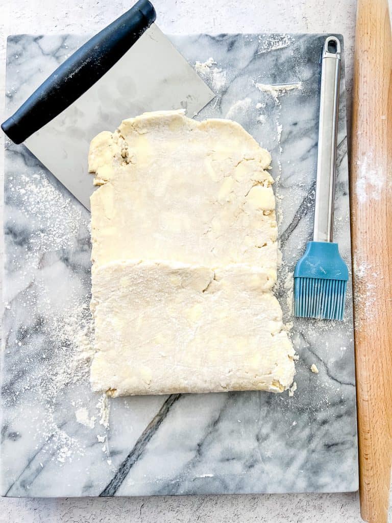 Folding the bottom third of a rolled out piece of Simple Rough Puff Pastry up and over the center of the dough.